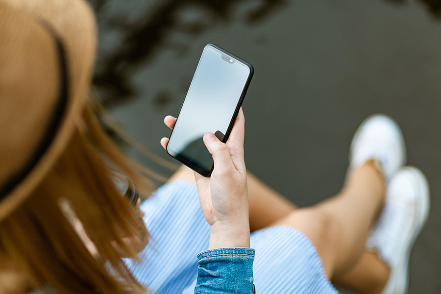 Frau schaut auf ihr Handy, ihr Handyvertrag ist zu teuer
